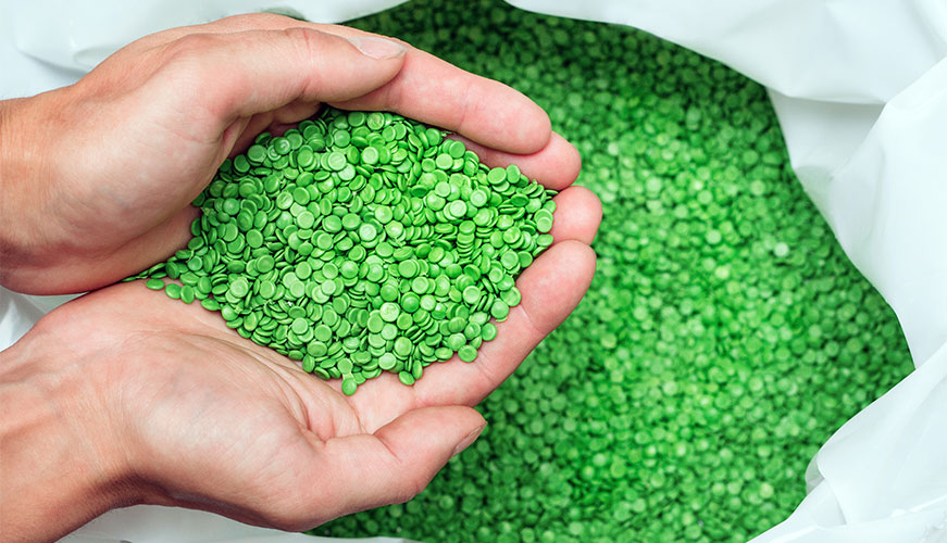 Close-up of hands holding green plastic pellets used for manufacturing and industrial production processes